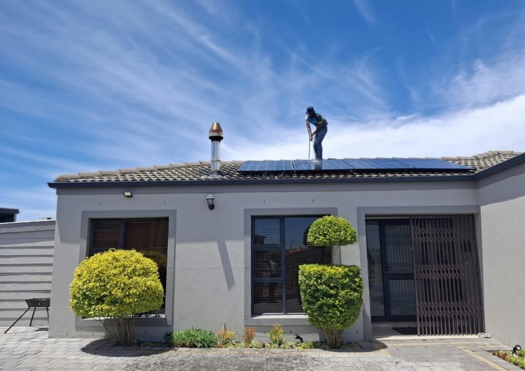 Photo montrant le nettoyage de panneaux photovoltaïques sur la toiture d'une maison.